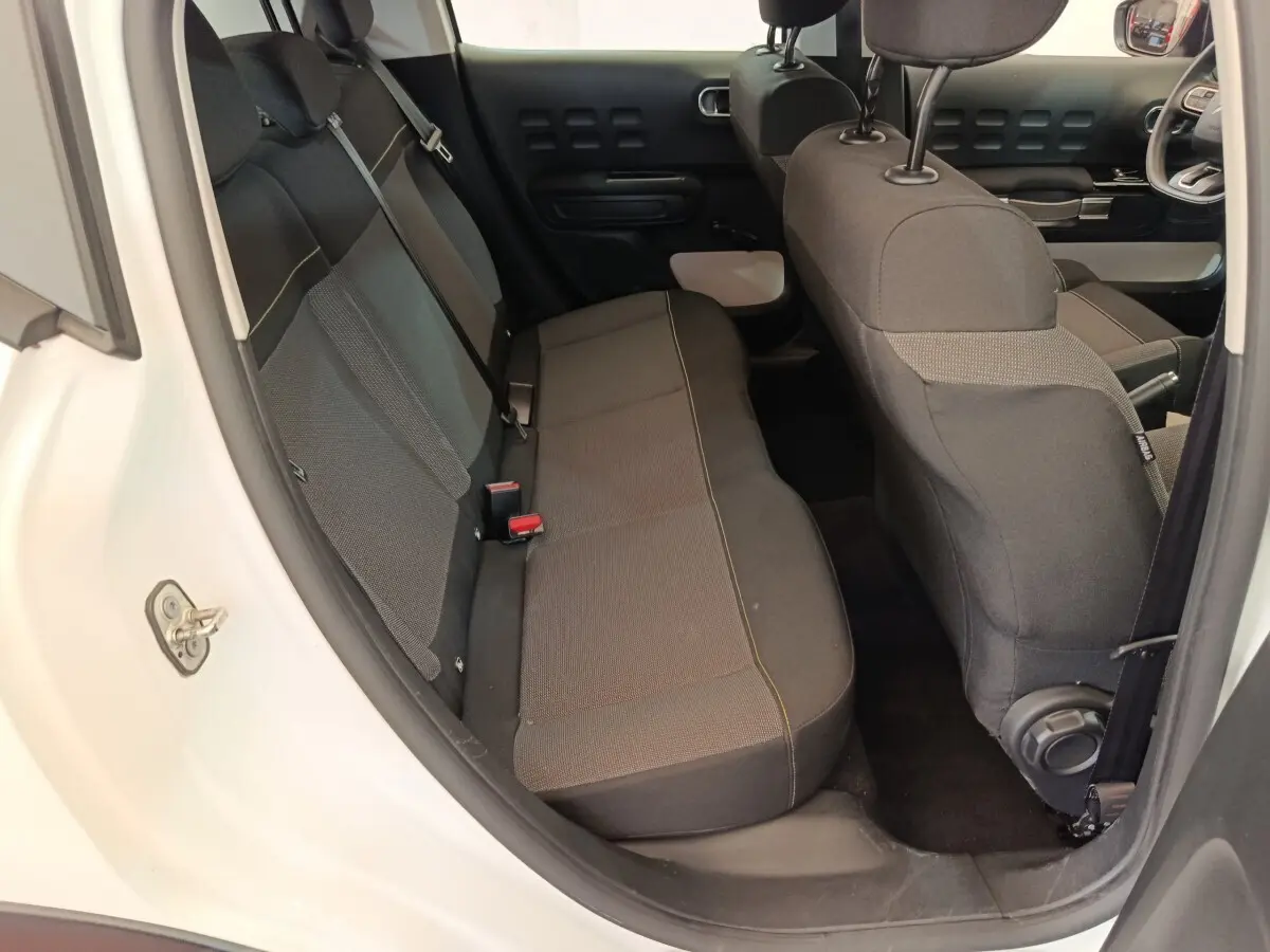Vue intérieure arrière côté gauche d'une Citroën C3 blanche 2020 avec banquette noire et détails de porte assortis.