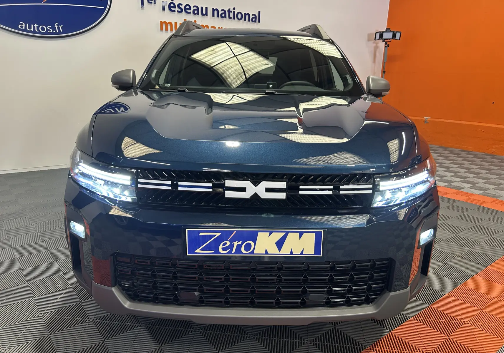 Vue frontale du Dacia Bigster bleu indigo avec phares LED allumés et calandre noire distinctive.