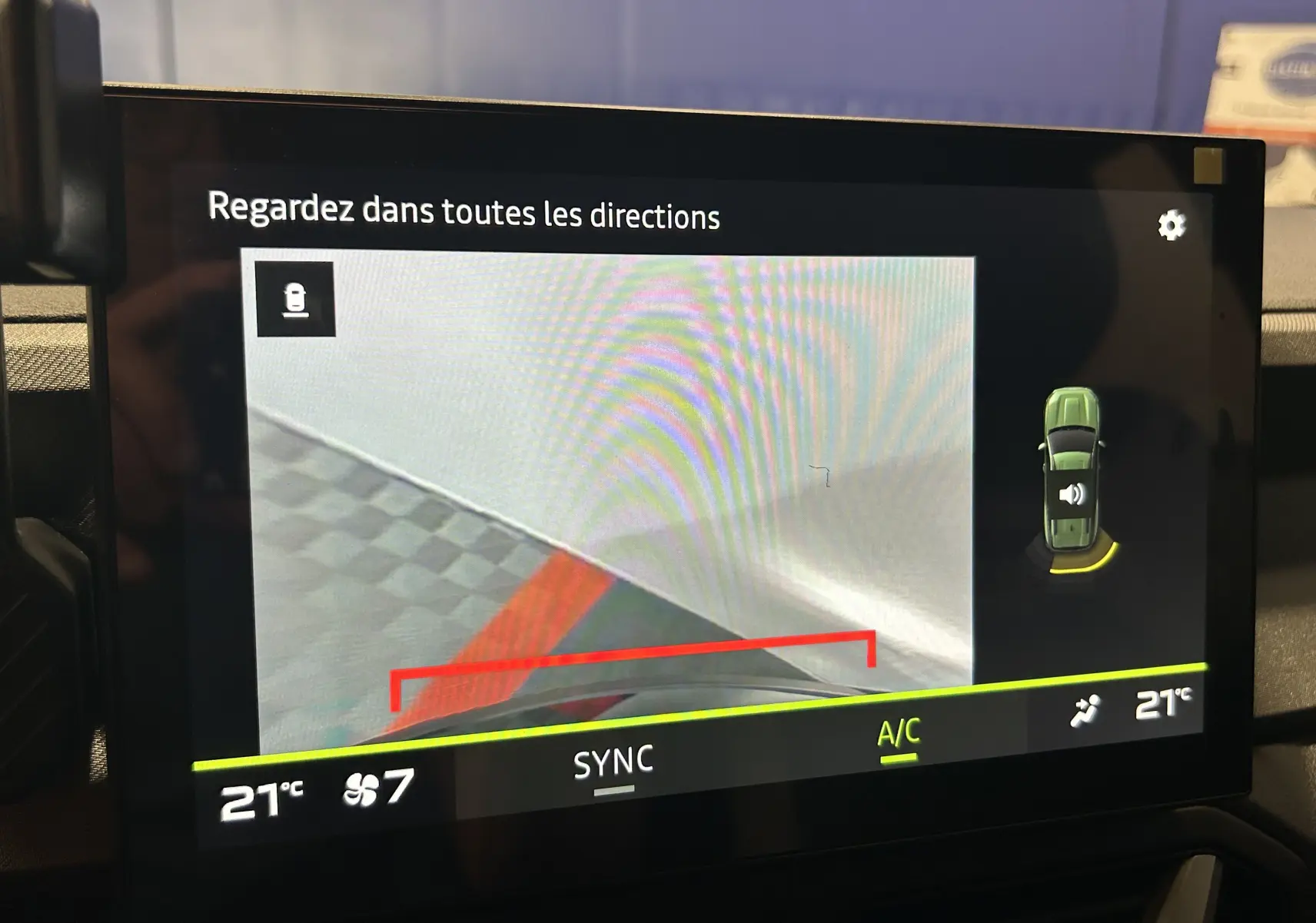Écran intérieur affichant la caméra de recul et l’alerte de proximité sur un Dacia Bigster bleu Indigo, vue du tableau de bord.