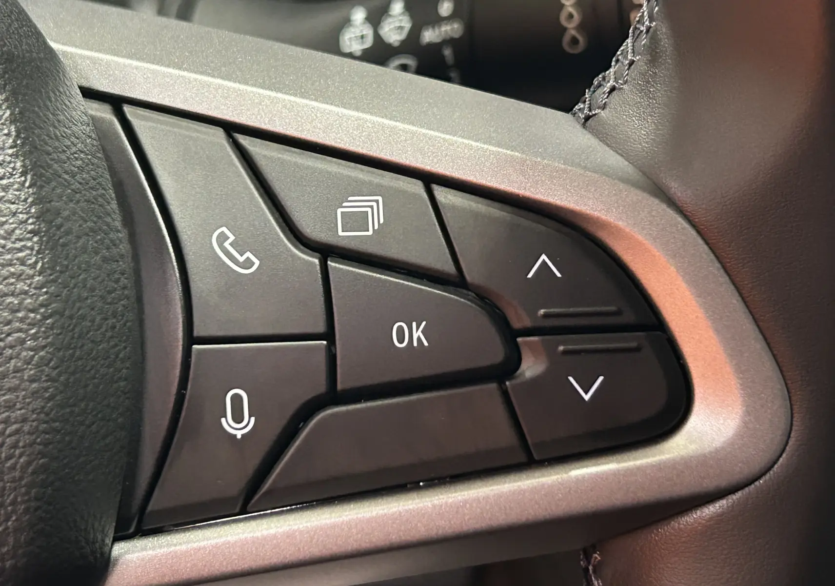 Gros plan sur les commandes multifonctions noires du volant du Dacia Bigster, entourées d’un cadre gris argenté.