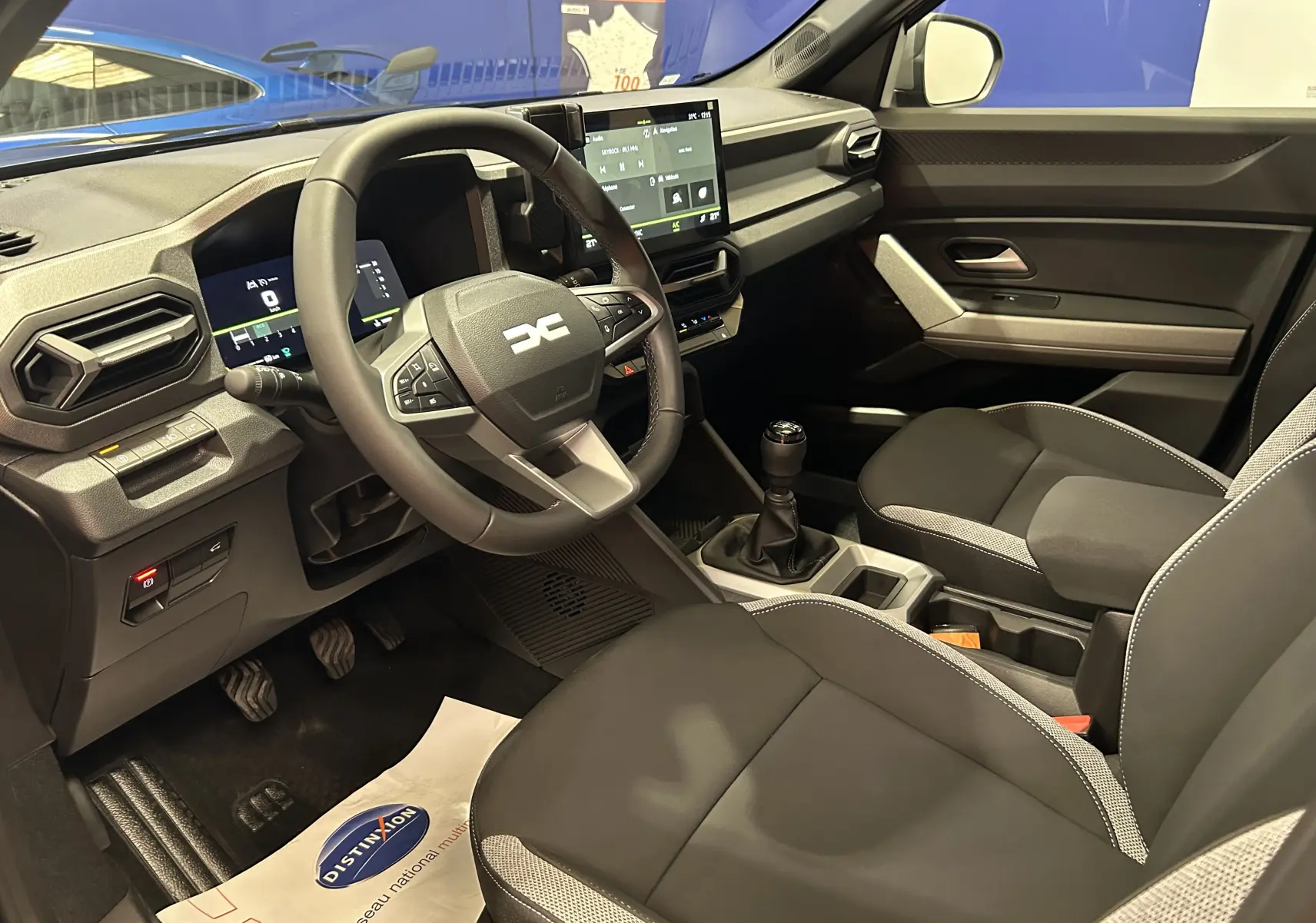 Vue intérieure côté conducteur du Dacia Bigster 2026 avec volant multifonction, écran tactile et sellerie tissu bicolore.