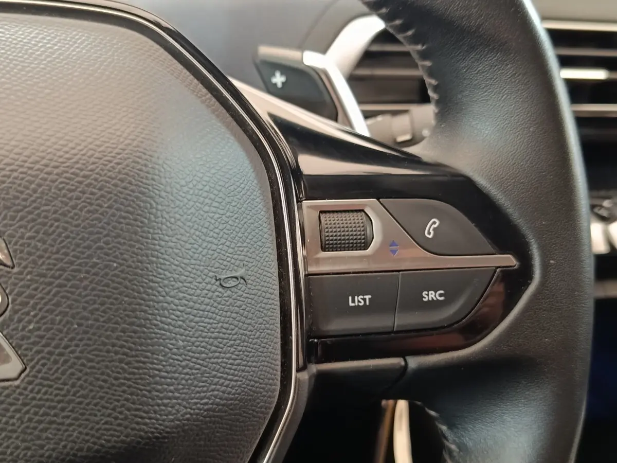 Gros plan sur le volant cuir noir de la Peugeot 5008 2020, avec commandes multifonctions et molette tactile à droite.