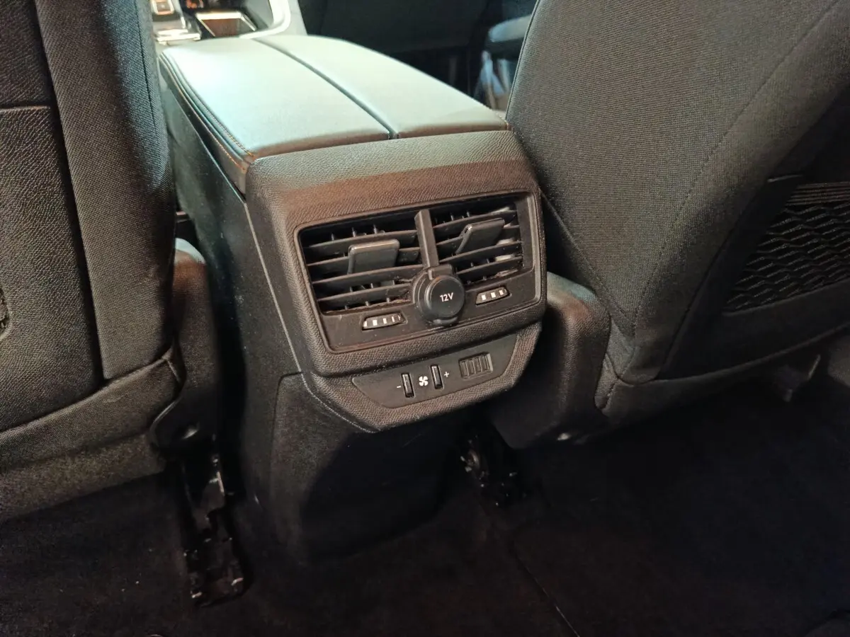 Vue rapprochée des commandes de ventilation arrière et prise 12V entre les sièges noirs du Peugeot 5008 2020.