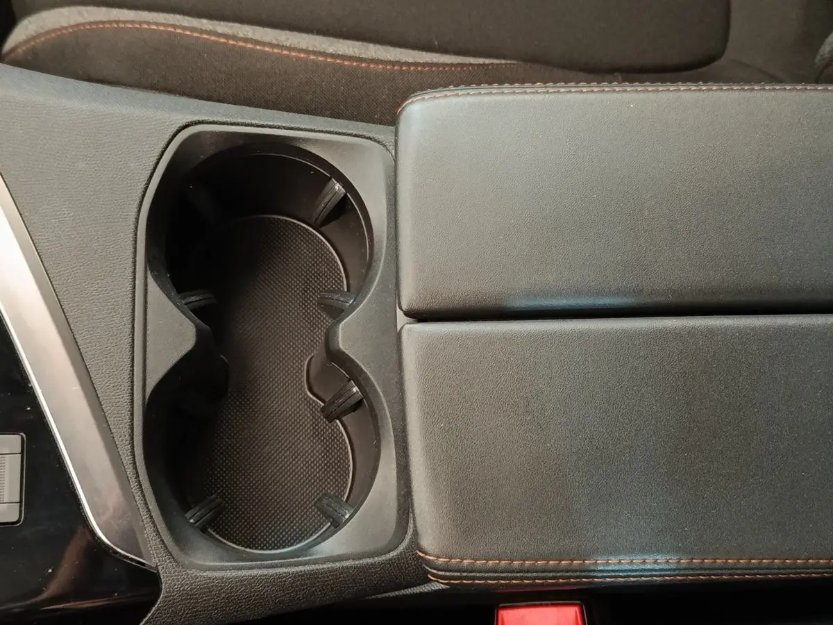 Gros plan sur la console centrale noire du Peugeot 5008 2020, avec porte-gobelets et accoudoir en cuir noir à surpiqûres marron.