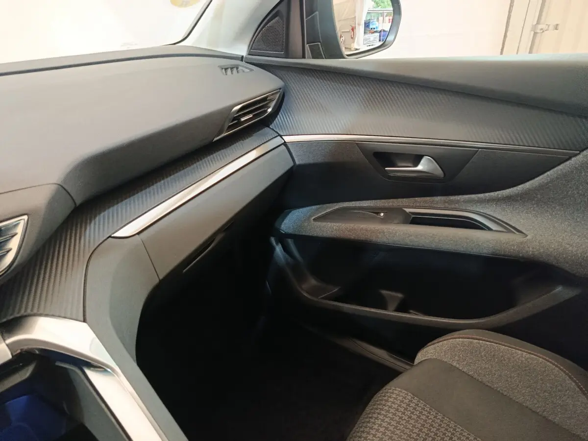 Vue intérieure côté passager du Peugeot 5008 2020 noir, avec tableau de bord et garnitures en finition carbone.