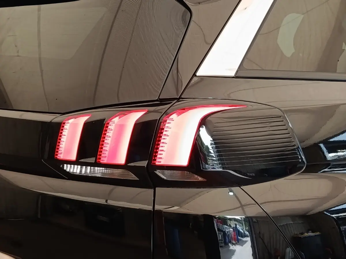 Gros plan sur les feux arrière droits allumés d’un Peugeot 5008 noir, soulignant les lignes modernes du véhicule.