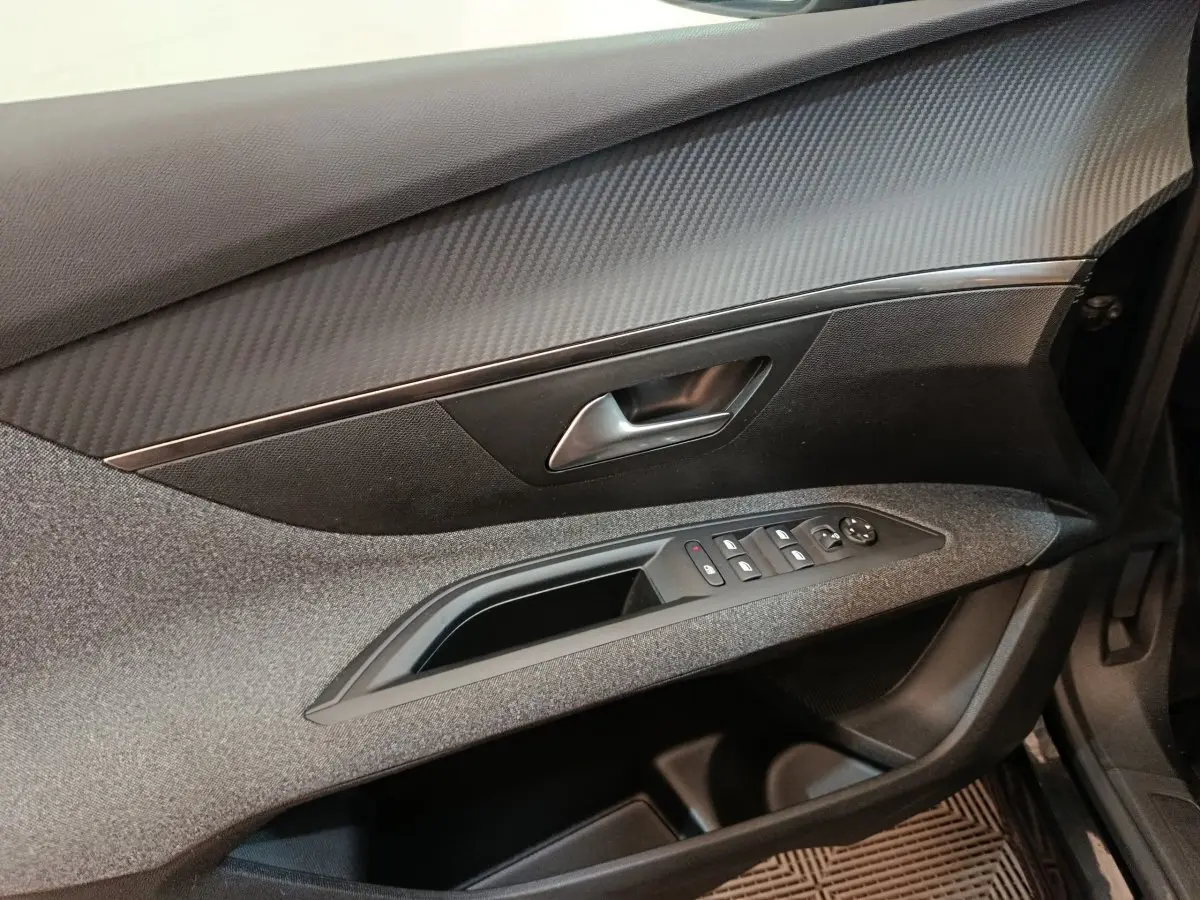 Vue rapprochée de la porte avant droite du Peugeot 5008 noir, avec commandes électriques et finition tissu/gris.