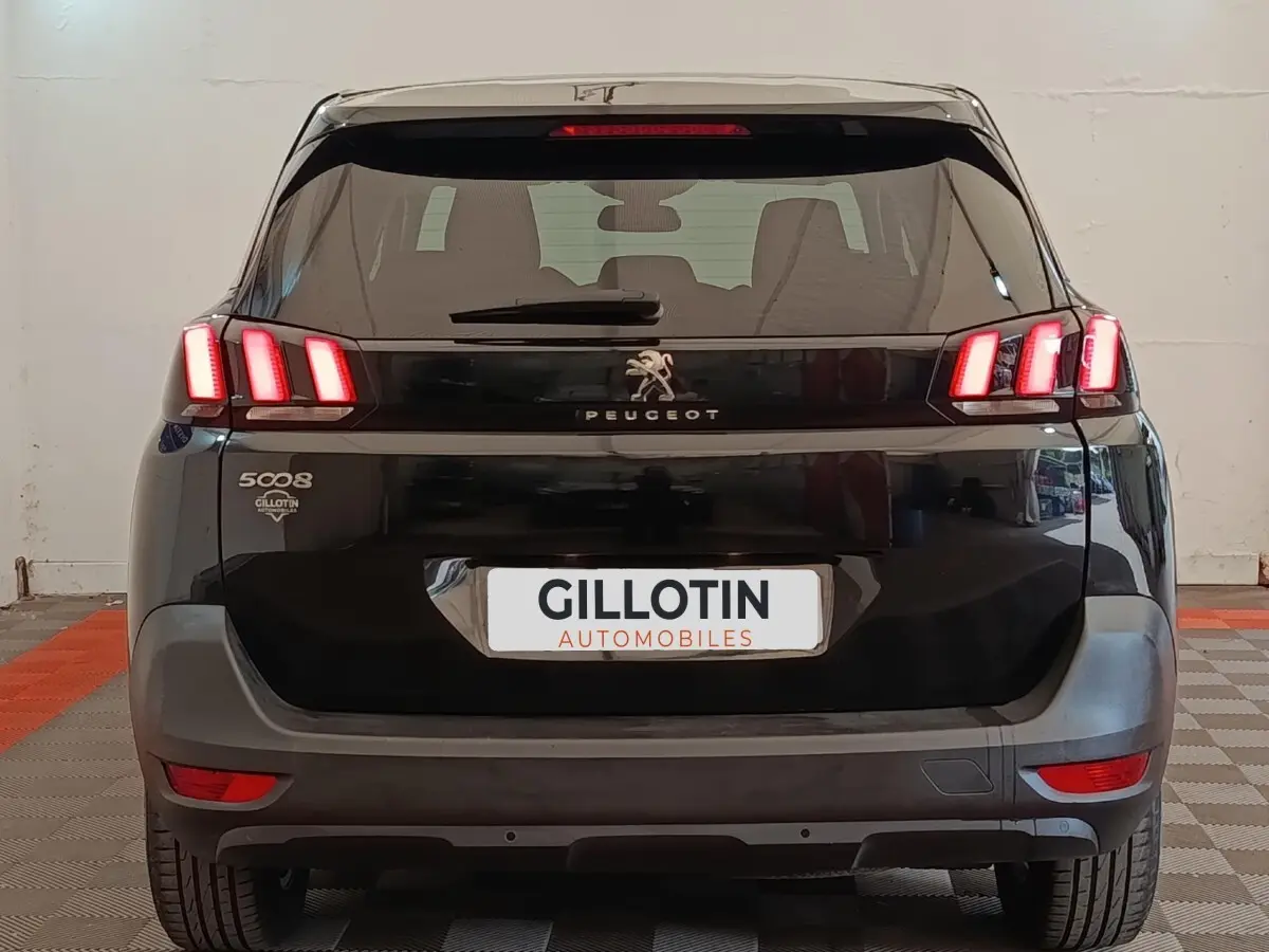 Vue arrière d'un Peugeot 5008 noir de 2020 avec feux LED allumés et logo Peugeot visible.