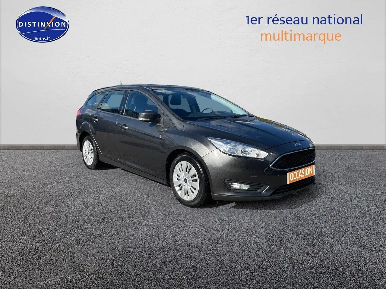 Ford Focus SW gris magnetic metal vue 3/4 avant droit sur fond neutre avec plaque occasion orange visible