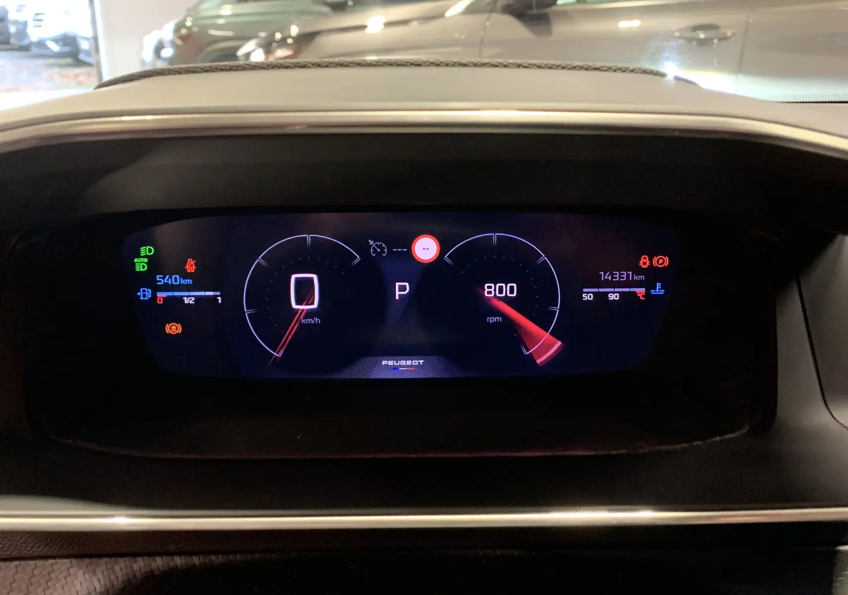 Tableau de bord numérique du Peugeot 2008 gris 2023 affichant vitesse à zéro et compte-tours à 800 rpm.