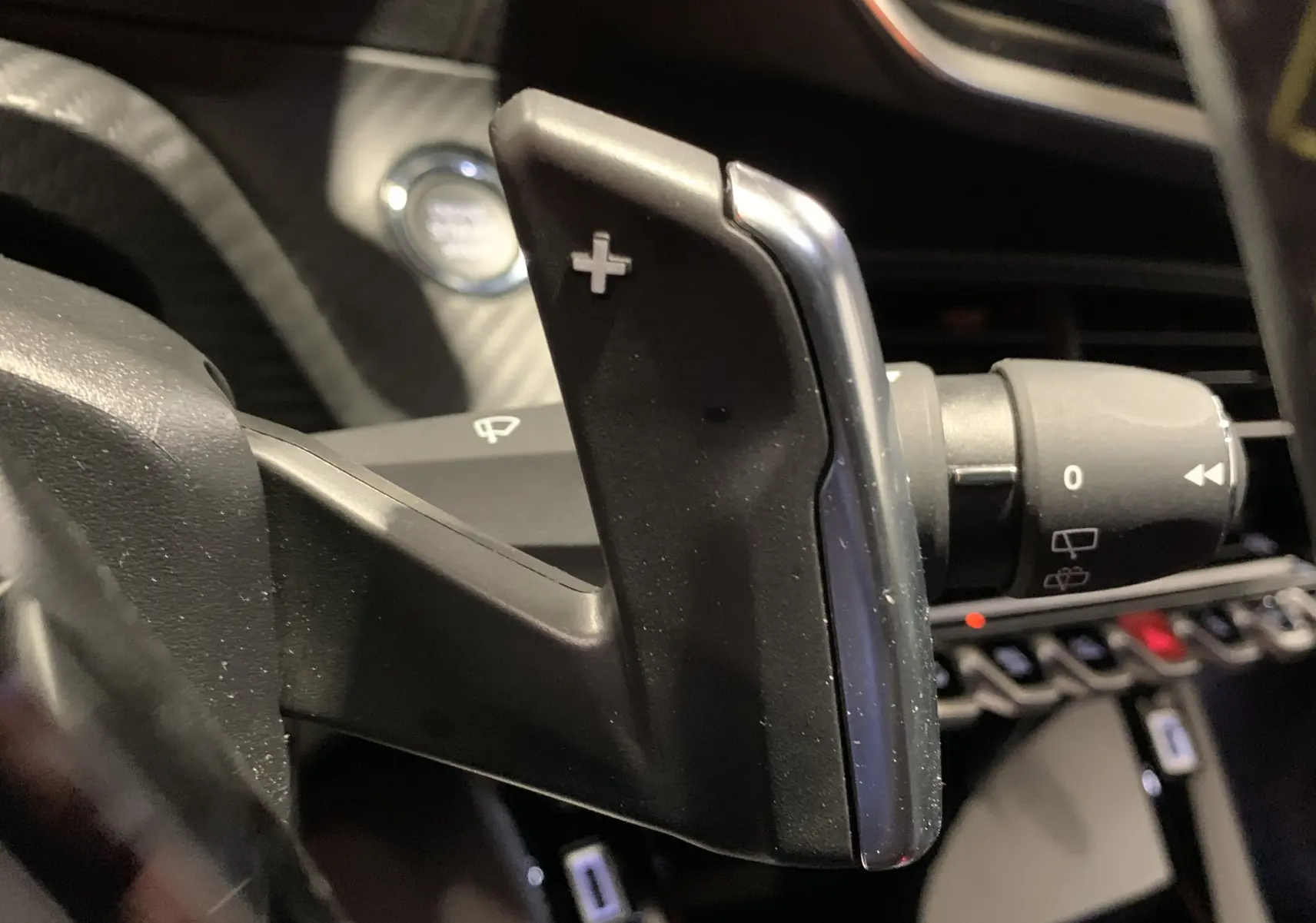 Gros plan sur la palette de changement de vitesse droite en plastique noir avec insert chromé dans l’habitacle d’un Peugeot 2008 gris 2023.