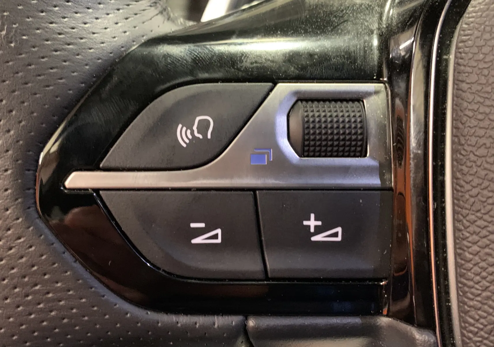 Gros plan sur les commandes du volant du Peugeot 2008 gris 2023, avec boutons de volume et activation vocale.