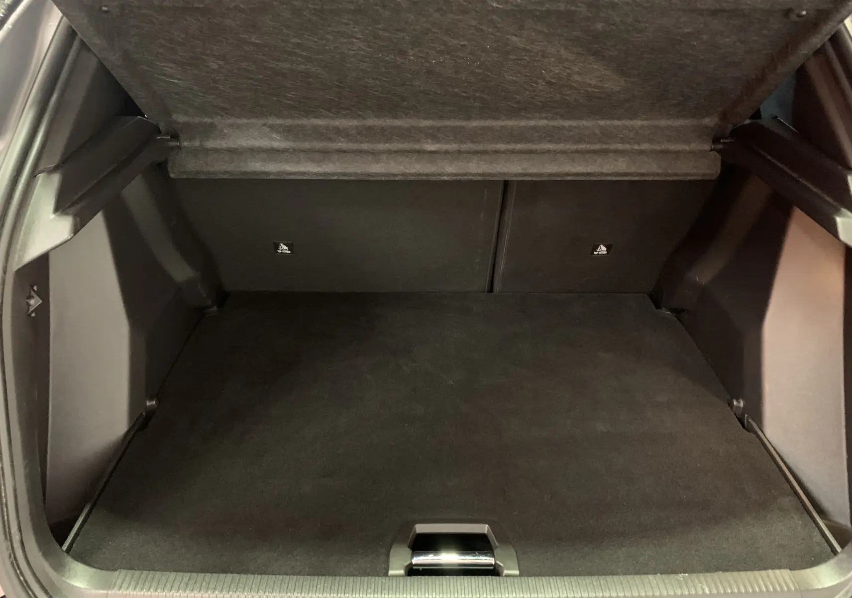 Coffre spacieux et vide du Peugeot 2008 BlueHDi 130 EAT8 GT 2023, vue intérieure arrière avec tapis noir.