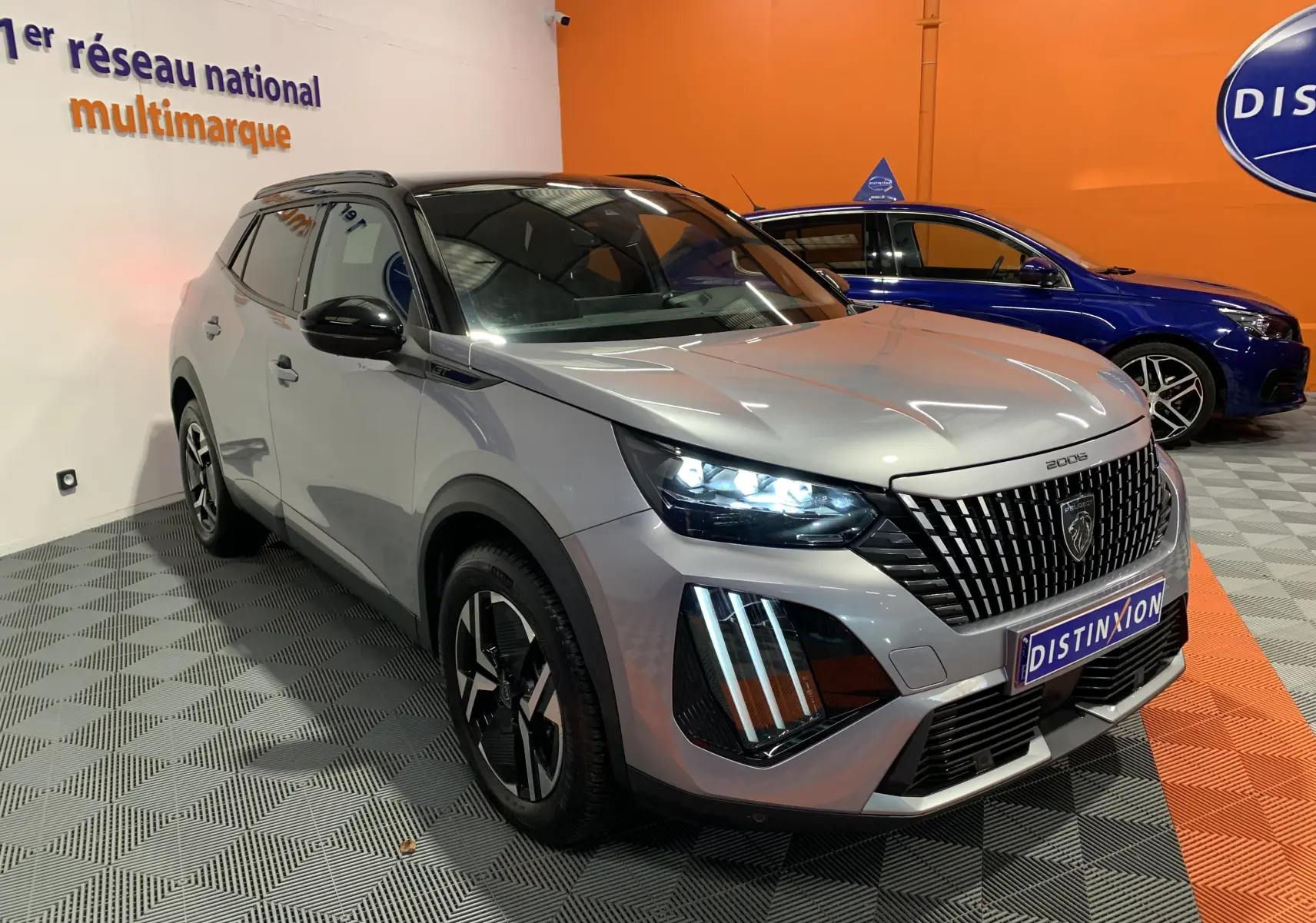 Peugeot 2008 gris en 3/4 avant droit, avec phares LED allumés et calandre distinctive en concession.