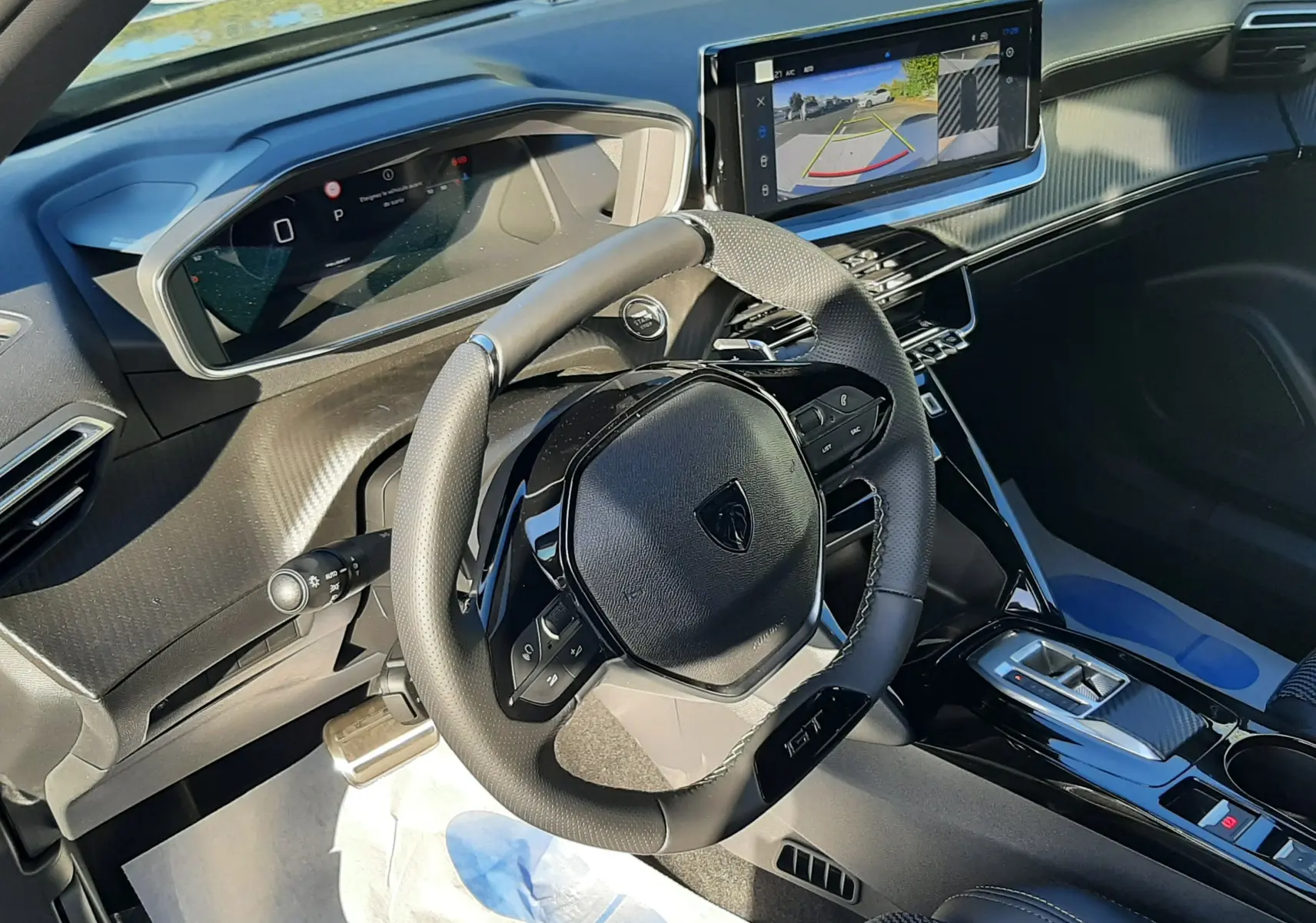 Intérieur du Peugeot 2008 1.2 Hybrid 145ch GT 2025, vue du poste de conduite avec volant compact et écran tactile affichant la caméra de recul.