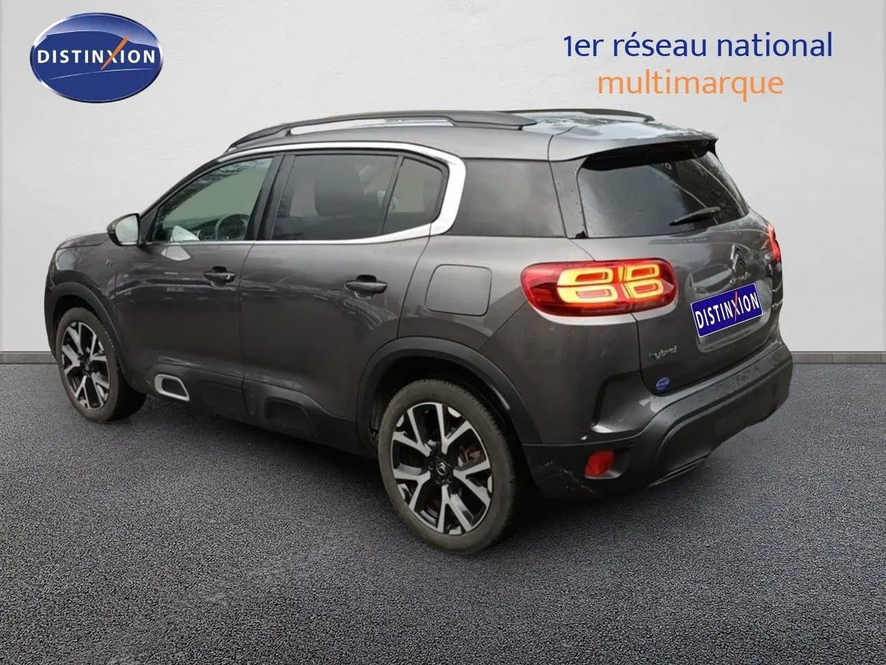 Vue 3/4 arrière droite d'un Citroën C5 Aircross hybride rechargeable gris platinium avec feux arrière allumés.