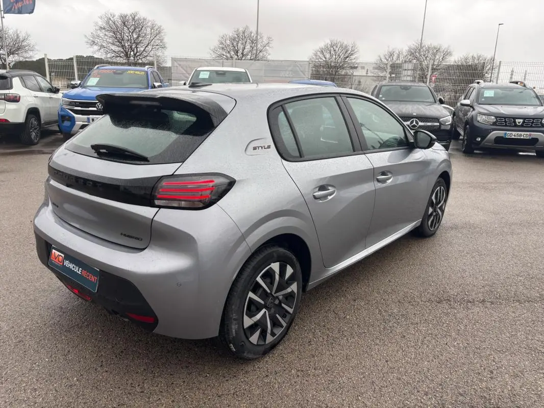Vue 3/4 arrière droite d'une Peugeot 208 Hybrid gris clair avec jantes 16 pouces et feux arrière LED distinctifs.
