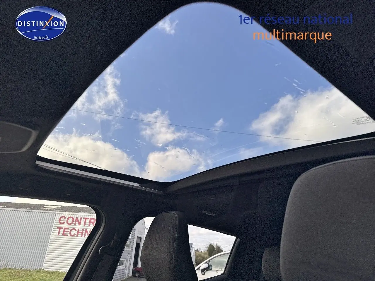 Toit panoramique en verre du Suzuki Vitara 2026 vu de l'intérieur, ciel bleu visible à travers.