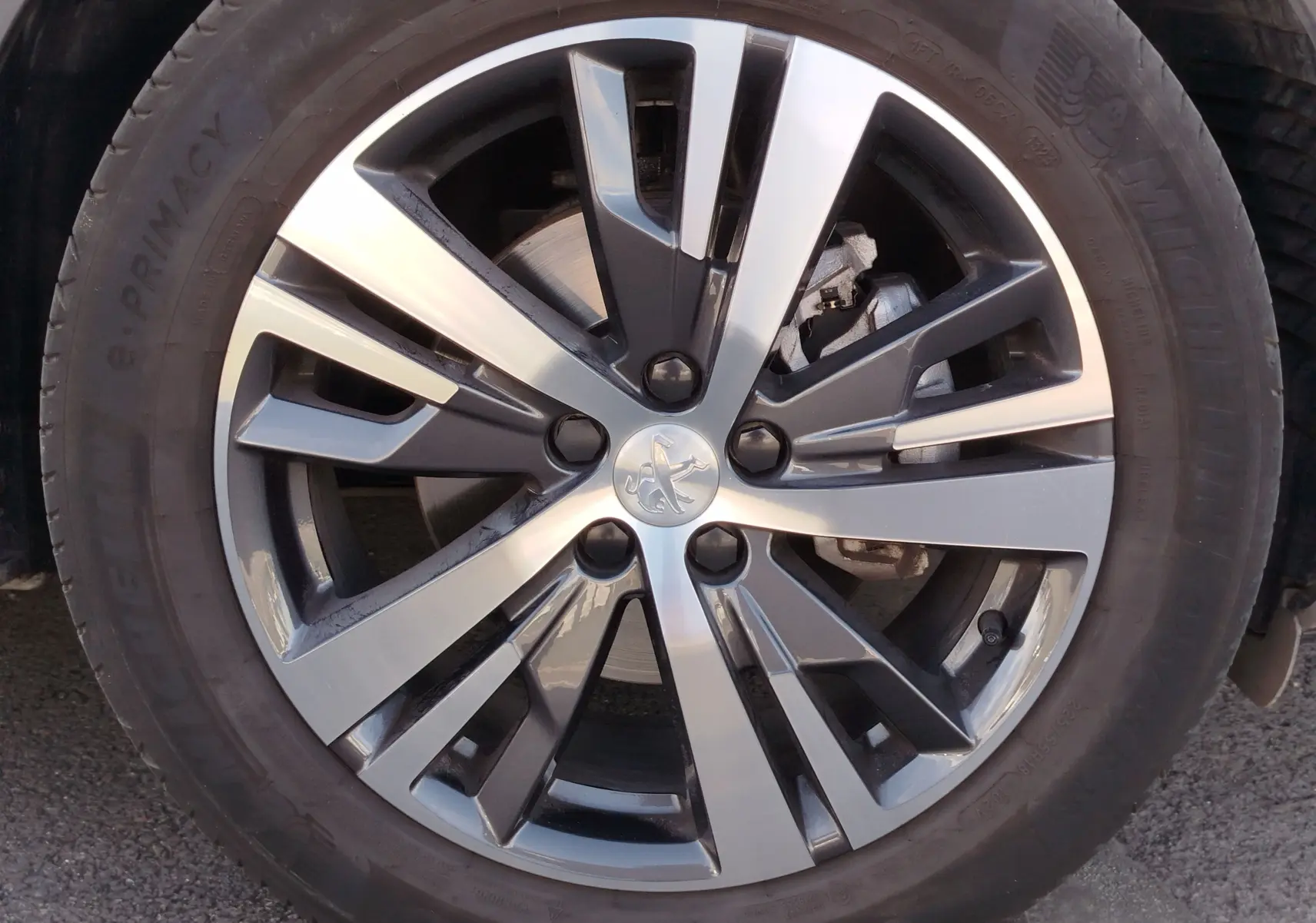 Gros plan sur la jante bi-ton argent et noir du Peugeot 3008 2023 Gris Platinium avec logo lion au centre.