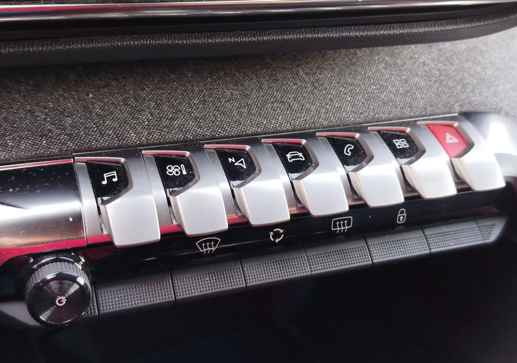 Gros plan sur les boutons de commande argentés et noirs du tableau de bord intérieur du Peugeot 3008 gris Platinium 2023.