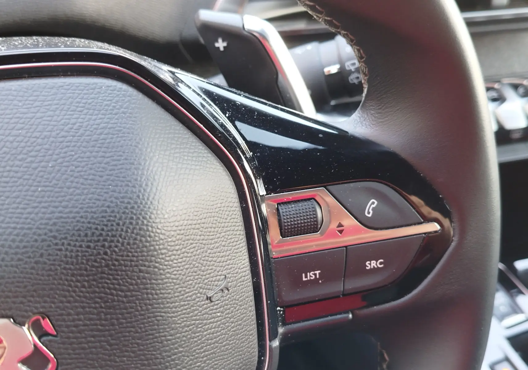 Gros plan sur les commandes du volant noir du Peugeot 3008 2023, avec molette et boutons fonction téléphone et audio.