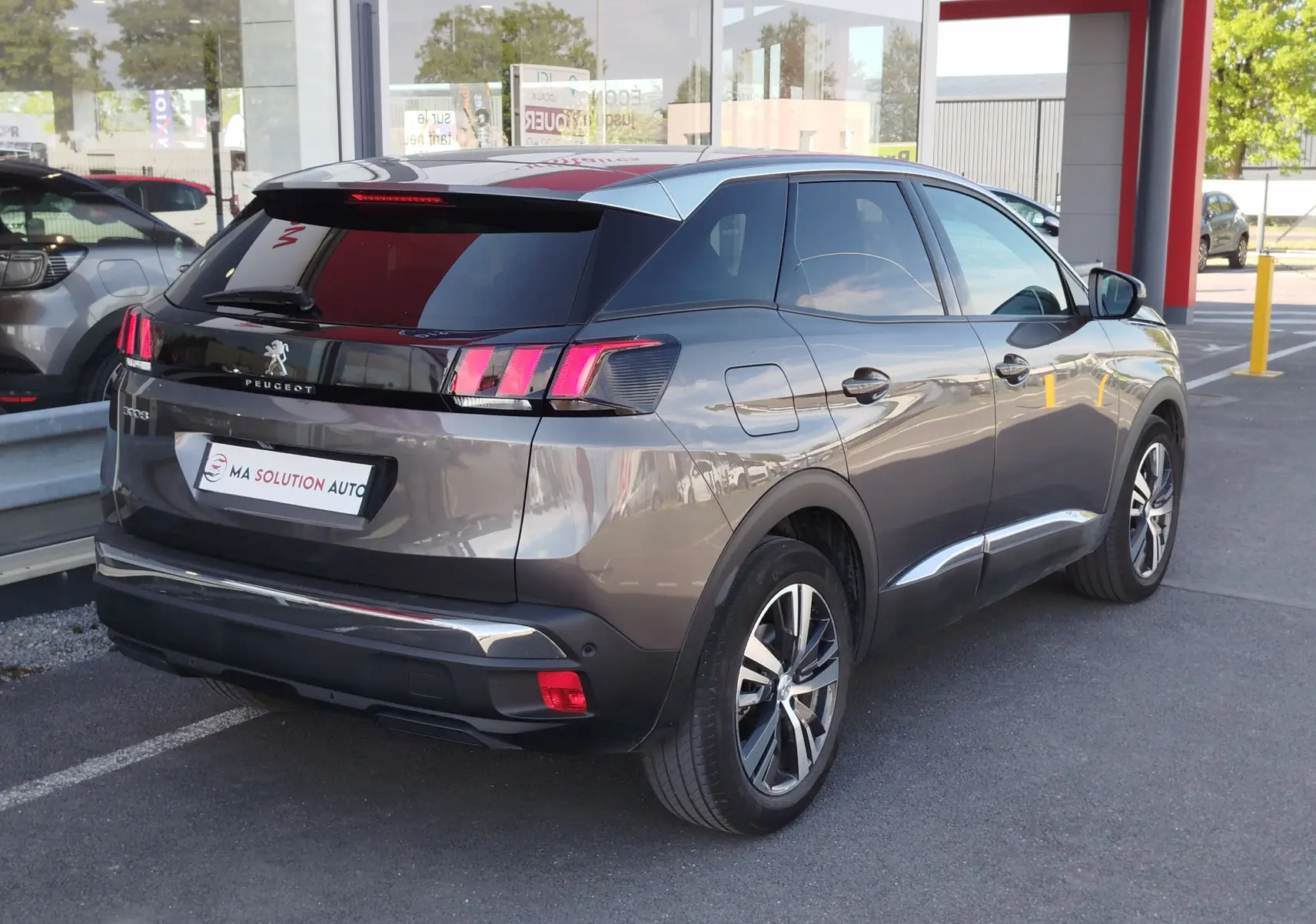Vue 3/4 arrière droite d’un Peugeot 3008 gris Platinium 2023 avec feux arrière à griffes et jantes bi-ton.