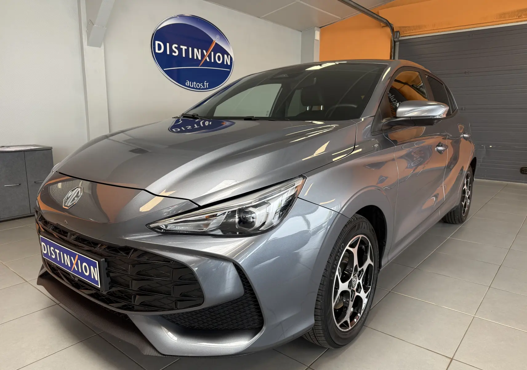 MG3 1.5 L Hybrid+ gris Hampstead, vue 3/4 avant droit, jantes alliage et calandre noire distinctive.