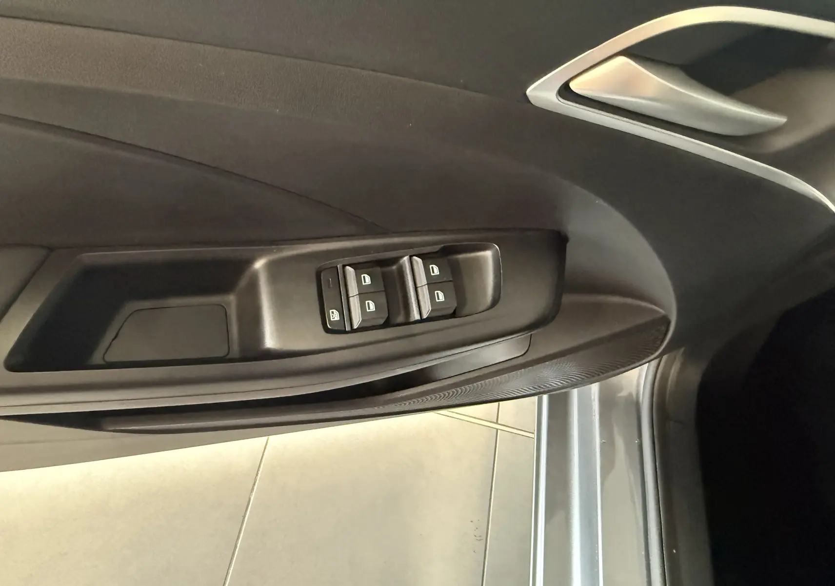 Vue rapprochée de la porte avant gauche du MG3 Hampstead Grey, montrant les commandes des vitres électriques et la poignée intérieure argentée.