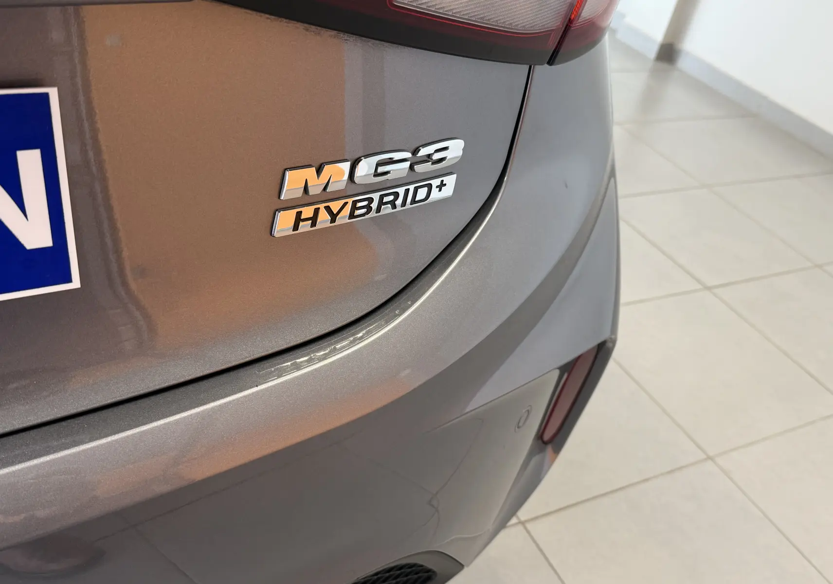 Gros plan sur l'arrière droit d'une MG3 Hybrid+ gris Hampstead avec logo et feu arrière partiel visible.