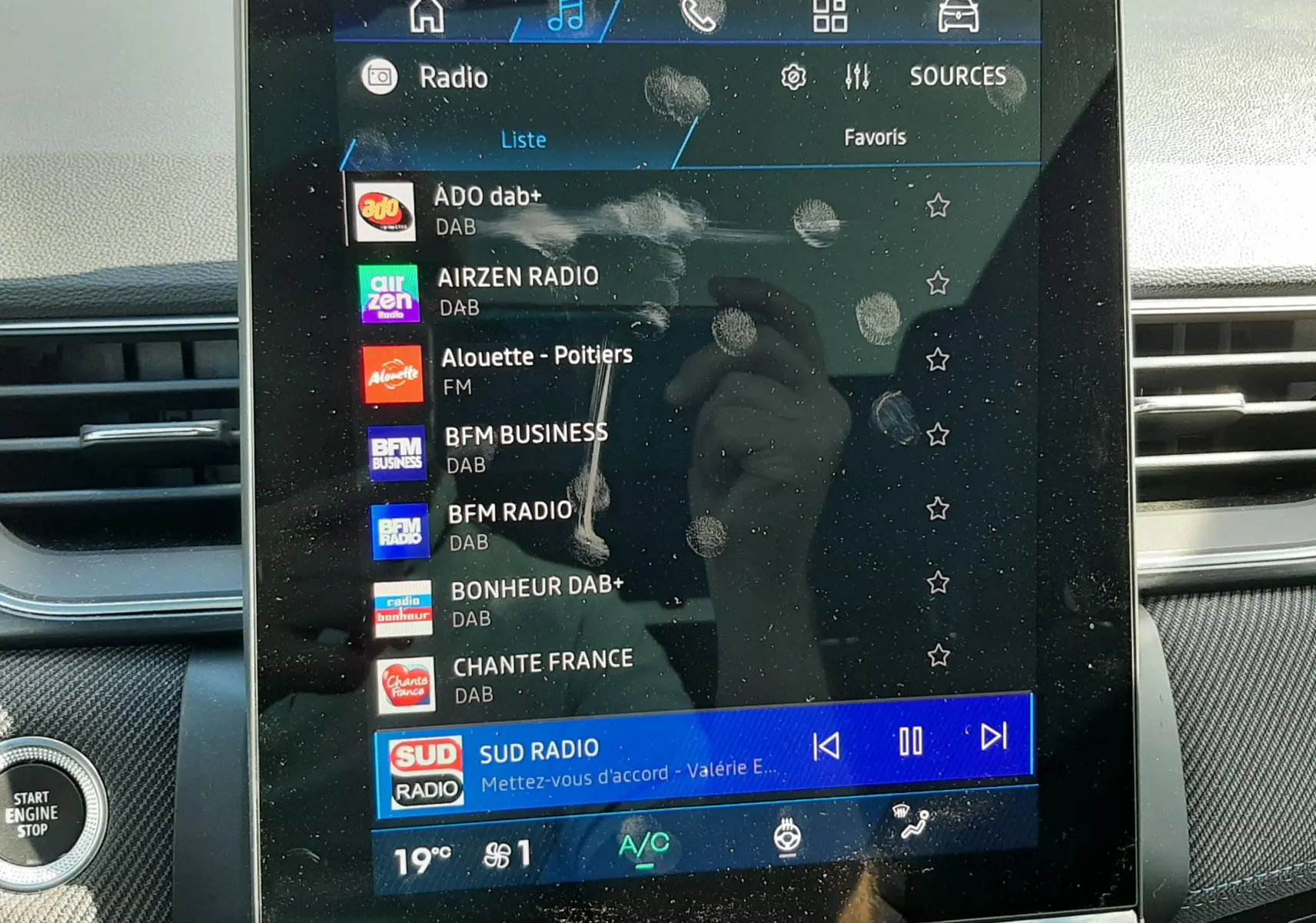 Écran tactile central du tableau de bord du Renault Symbioz gris Rafale, affichant la liste des radios DAB avec traces de doigts visibles.