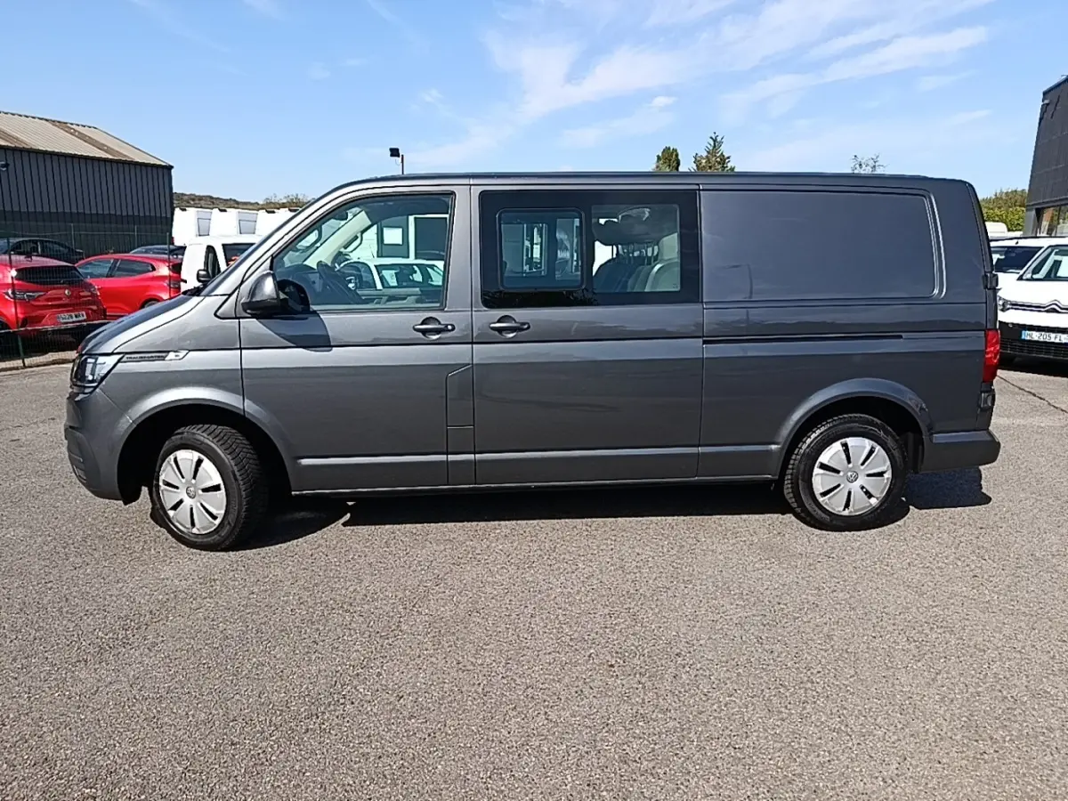Vue latérale droite d’un Volkswagen Transporter gris foncé 2022, fourgon utilitaire avec vitres avant et portes coulissantes.