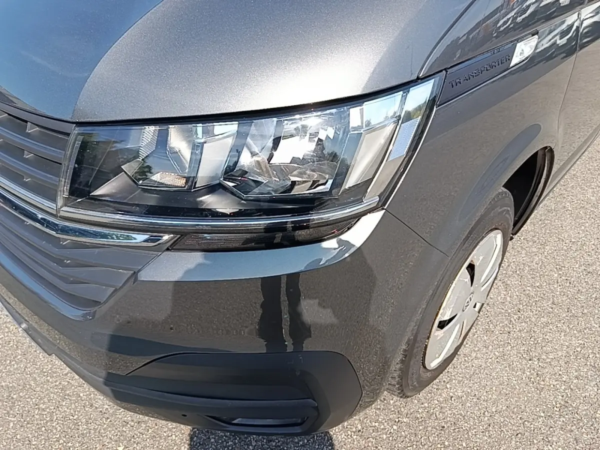 Gros plan sur l'avant droit gris foncé du Volkswagen Transporter 2.0 TDi avec phares et calandre visibles.