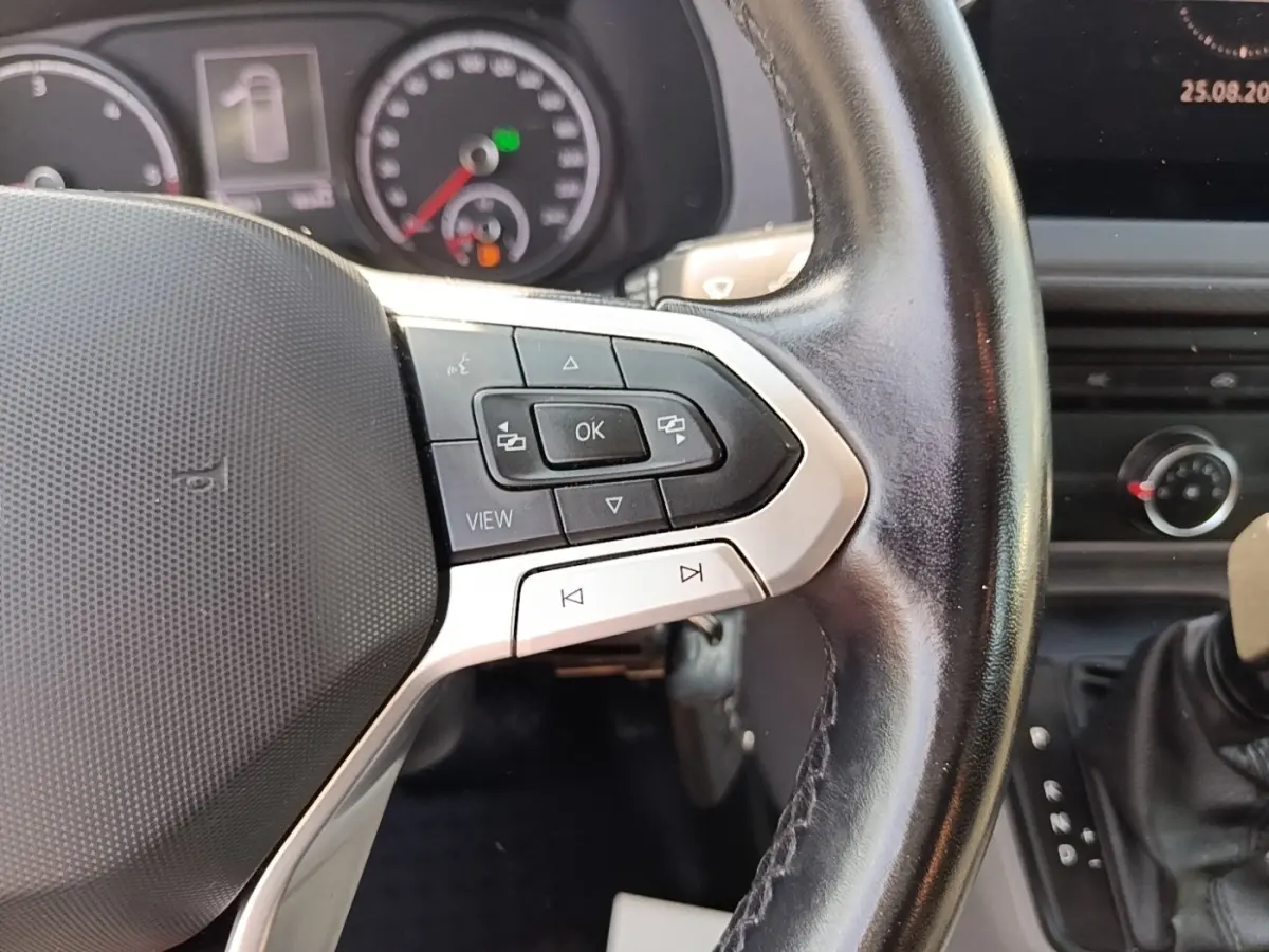 Gros plan sur le volant cuir multifonctions du Volkswagen Transporter 2.0 TDi 150 DSG7, tableau de bord en arrière-plan.