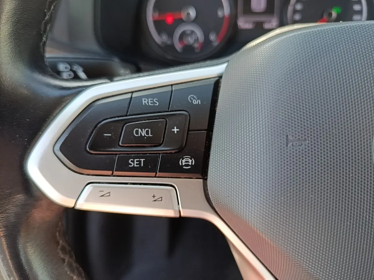 Gros plan sur le volant cuir multifonctions gris du Volkswagen Transporter 2.0 TDi 150 DSG7, avec commandes de régulateur.