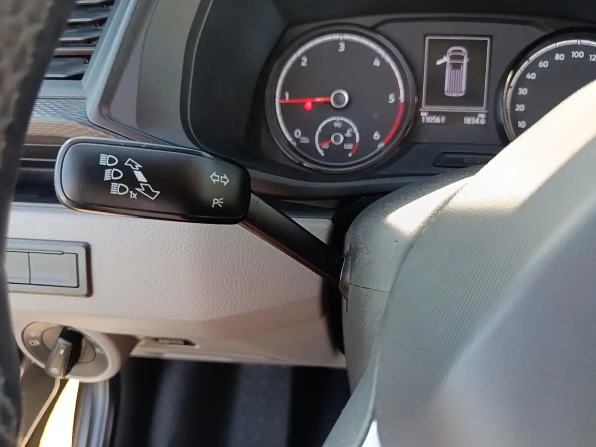 Gros plan intérieur sur le tableau de bord et levier de clignotant du Volkswagen Transporter gris foncé, affichage des compteurs visible.