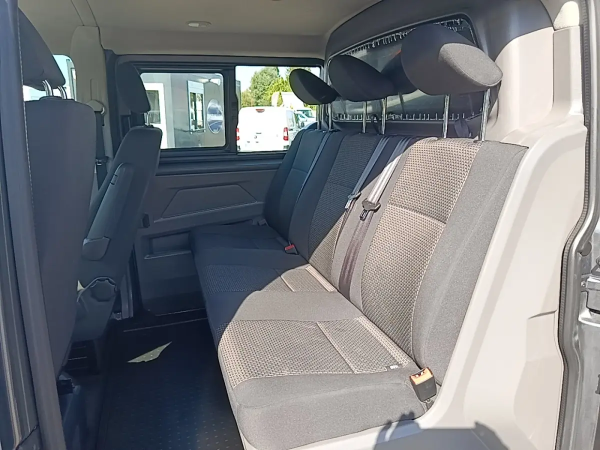Vue intérieure côté droit sur la banquette arrière grise du Volkswagen Transporter 2022 avec appuie-têtes et ceinture de sécurité.