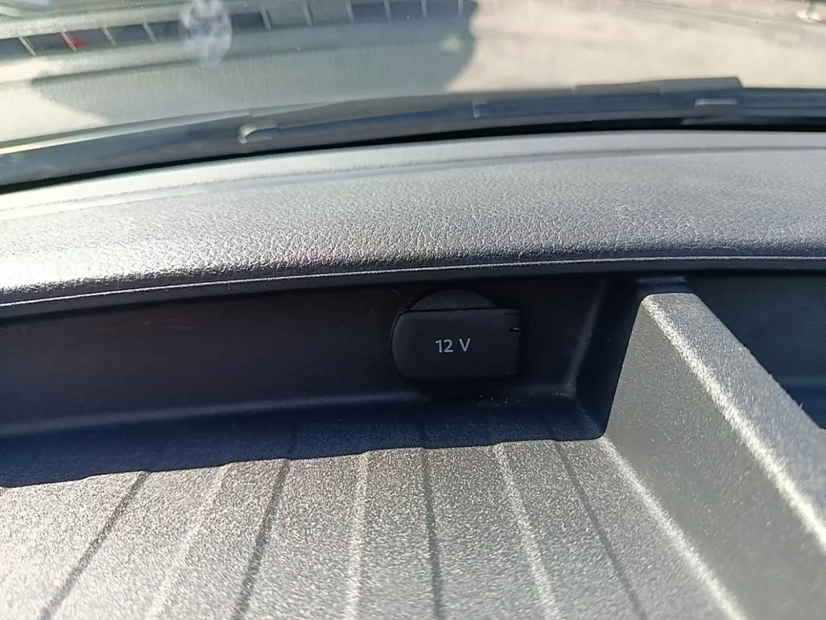 Prise 12V noire en gros plan sur le tableau de bord d’un Volkswagen Transporter gris foncé, vue intérieure frontale.