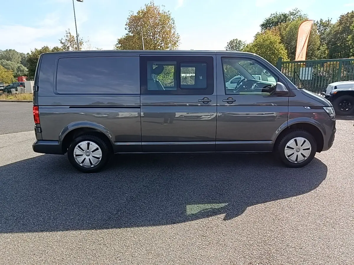 Vue de profil côté droit d’un Volkswagen Transporter gris foncé avec vitres avant et portières coulissantes arrière.