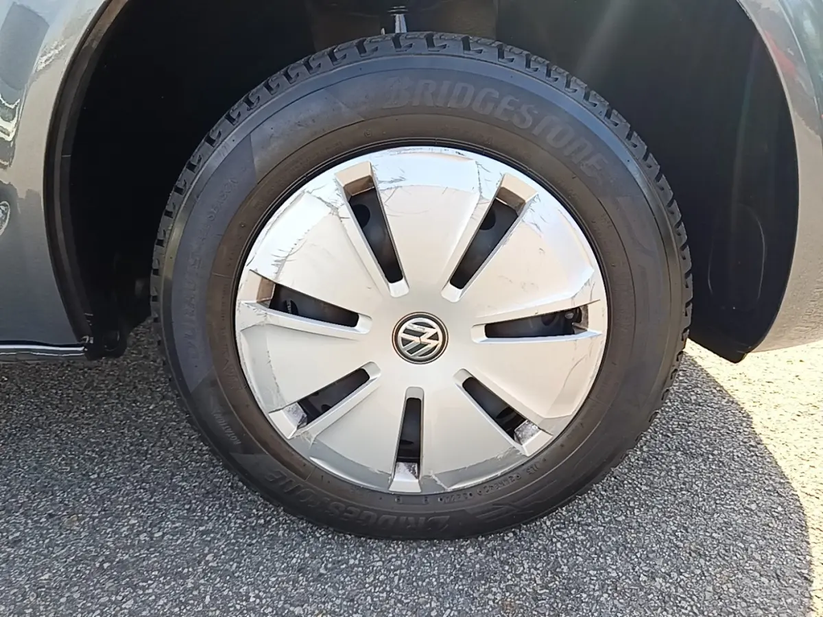 Gros plan sur la roue avant droite du Volkswagen Transporter gris foncé, jante acier avec enjoliveur VW marqué.