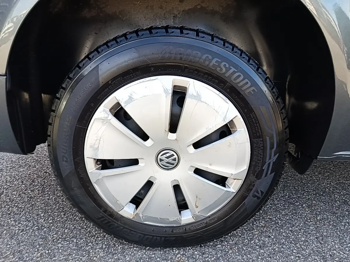 Gros plan sur la roue avant droite gris foncé du Volkswagen Transporter 2.0 TDi 150 DSG7 avec enjoliveur blanc marqué VW.