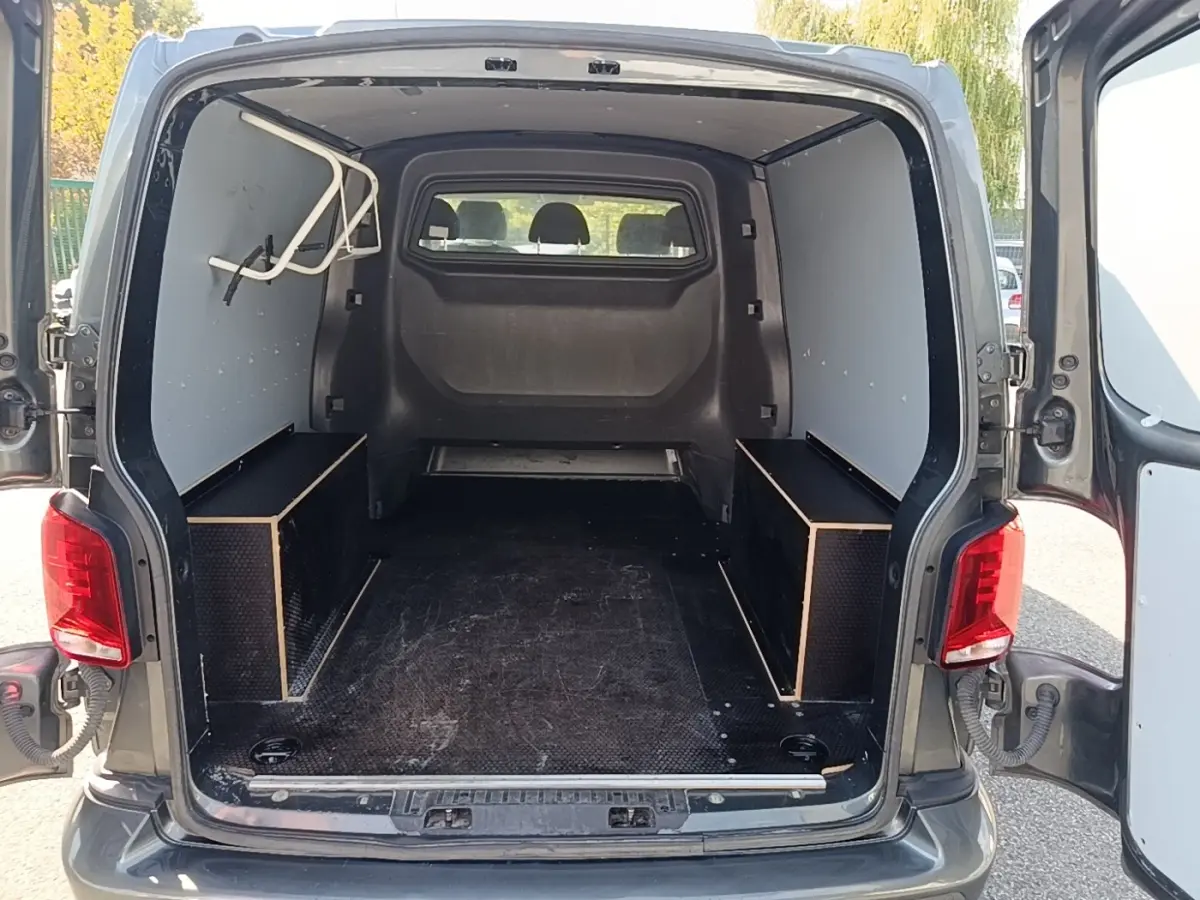 Vue arrière du Volkswagen Transporter gris foncé 2022 avec portes ouvertes et espace de chargement vide.