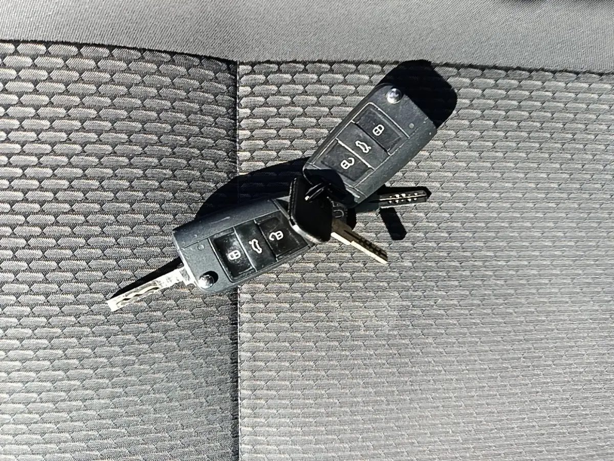 Gros plan sur deux clés Volkswagen noires posées sur un tissu gris texturé, sans vue du véhicule.