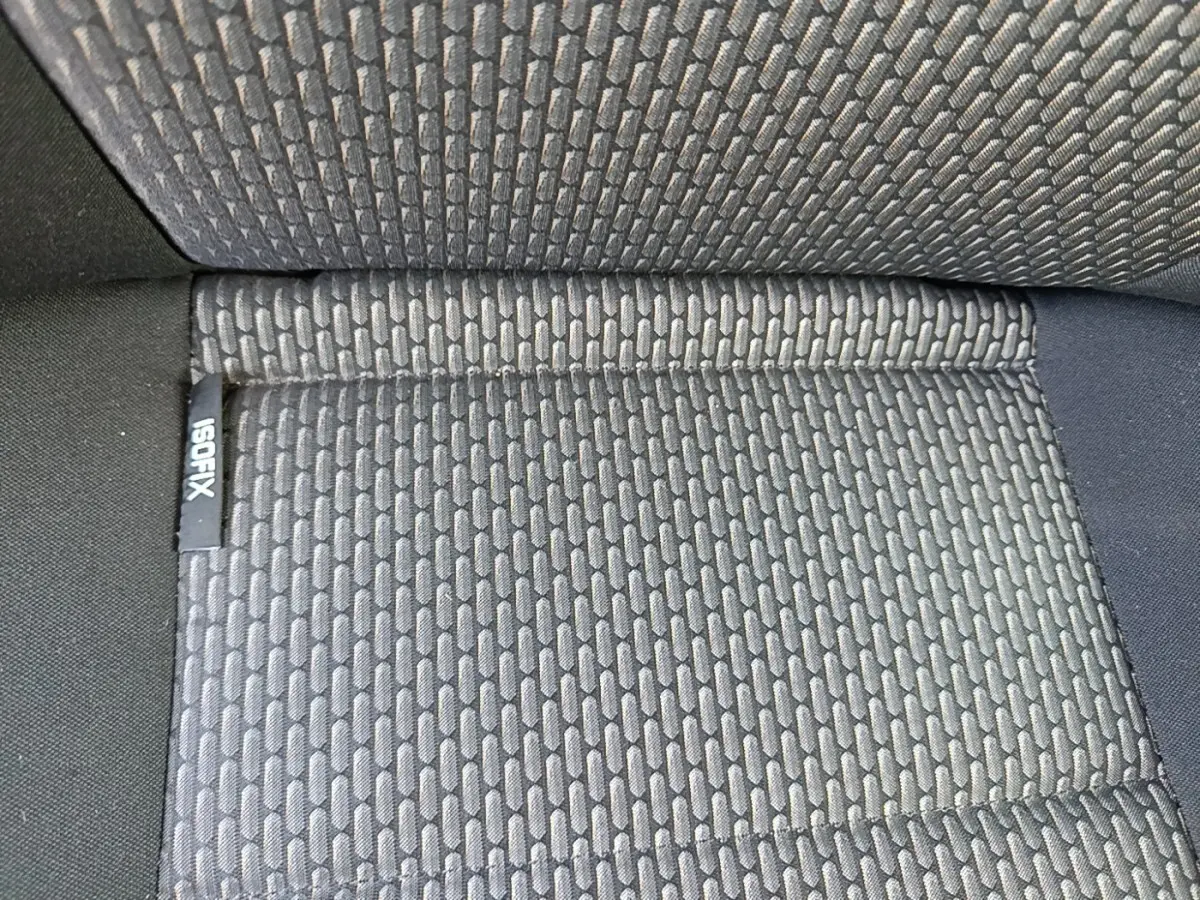 Gros plan sur le tissu gris foncé du siège arrière du Volkswagen Transporter 2022 avec étiquette ISOFIX visible.