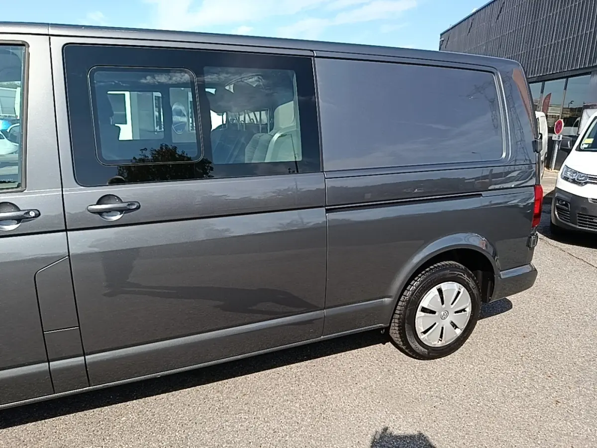 Vue latérale droite d'un Volkswagen Transporter 2.0 TDi gris foncé avec vitres arrière teintées et jantes acier.