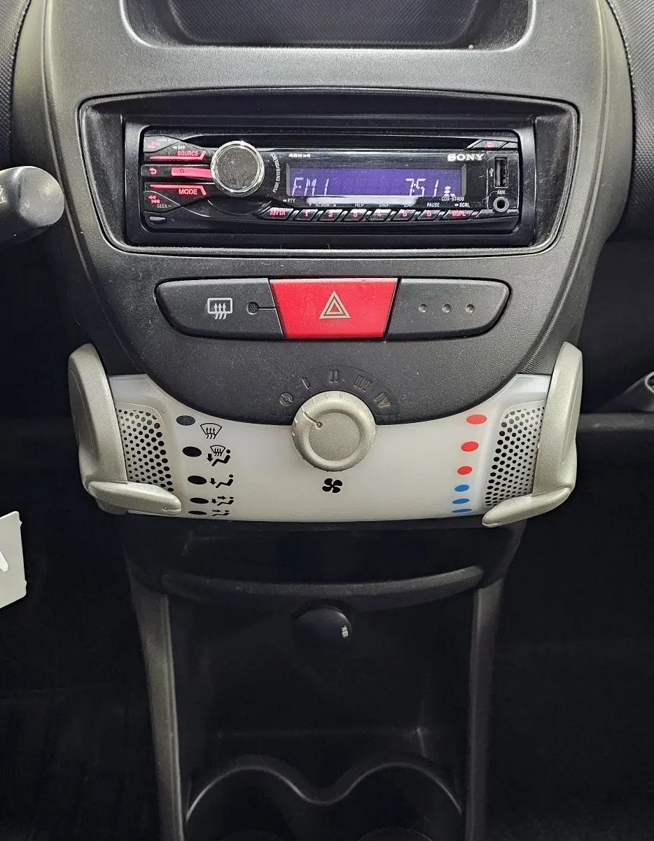 Vue rapprochée du tableau de bord de la Peugeot 107 2013 avec radio Sony et levier de vitesse manuel.