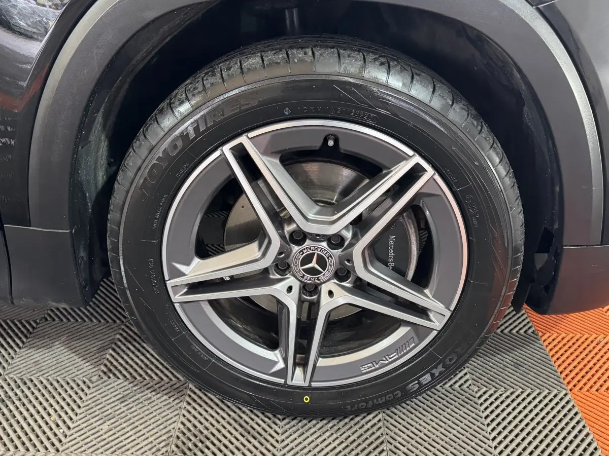 Gros plan sur la roue avant droite noire d’un Mercedes GLB 200 d AMG Line, jante alliage à cinq branches.