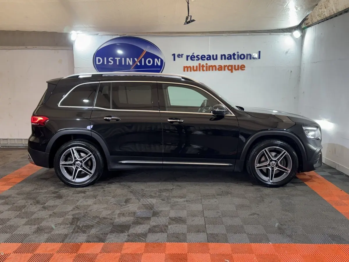 Vue latérale droite d’un Mercedes GLB 200 d AMG Line noir, avec jantes alliage et rails de toit chromés.