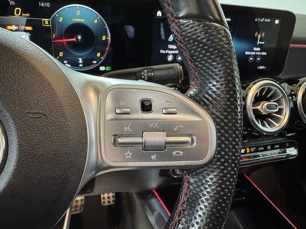 Gros plan sur le volant en cuir noir perforé avec commandes intégrées et tableau de bord numérique du Mercedes GLB 200 d AMG Line.