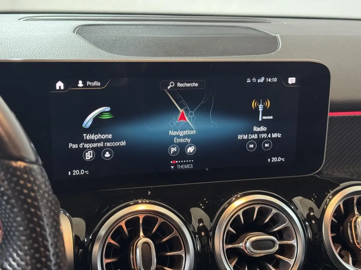 Vue rapprochée de l'écran tactile central du tableau de bord noir du Mercedes GLB 200 d AMG Line affichant navigation et radio.