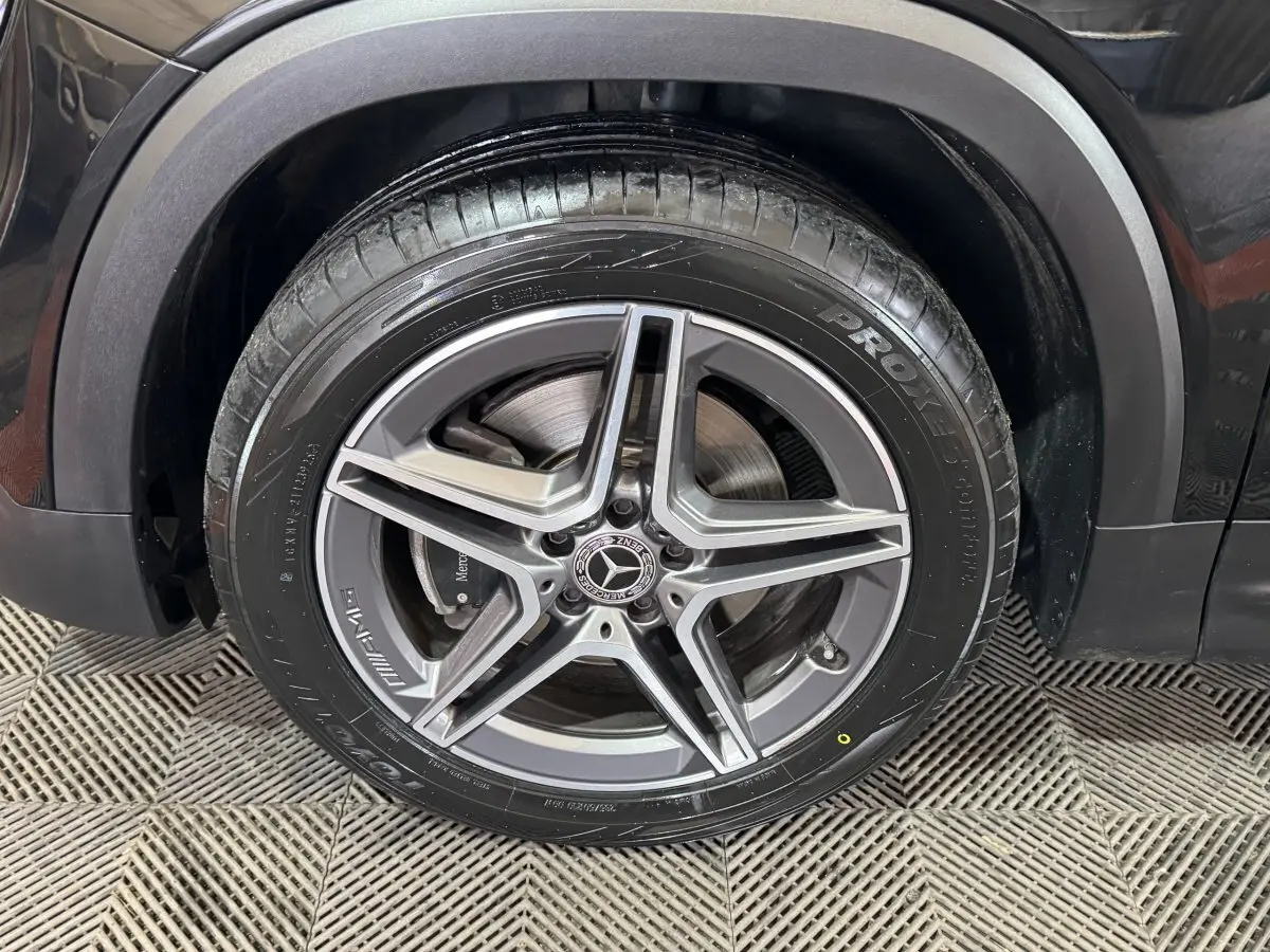 Gros plan sur la roue avant droite noire d’un Mercedes GLB 200 d AMG Line avec jante alliage 5 branches.